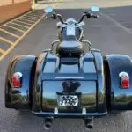 A motorcycle with three wheels parked in the street.