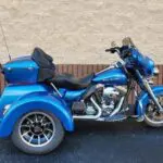 A blue motorcycle parked in the street next to a building.