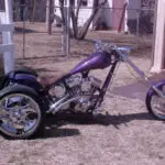 A purple motorcycle parked in the grass.