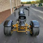 A motorcycle with three wheels parked on the side of a road.