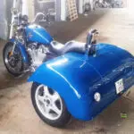 A blue motorcycle with a side car parked in the street.