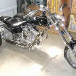 A motorcycle is parked in the garage with its front wheel up.