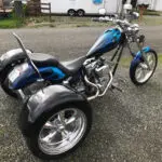 A blue and silver three wheeled motorcycle parked on the street.