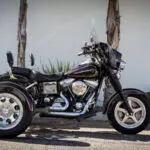 A black motorcycle parked in front of some trees.