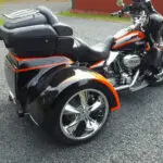 A motorcycle with orange trim is parked on the street.