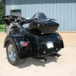 A black motorcycle with a side car parked on the ground.