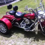 A red motorcycle with two seats parked in the grass.