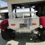 A red and silver car parked in front of a garage.