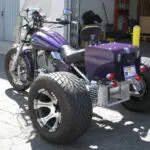 A purple motorcycle with large tires parked in the driveway.