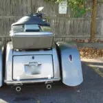 A motorcycle is parked in the street with its back end open.