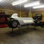 A white car sitting in the middle of a garage.