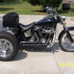 A motorcycle with a side car parked on the sidewalk.