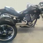 A black motorcycle parked in a garage with its wheels down.