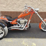 A orange and black motorcycle parked on the side of a road.