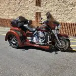 A red motorcycle parked in the street near a building.