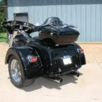 A black motorcycle with a side car parked on the sidewalk.