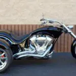 A black motorcycle parked in front of a brick wall.