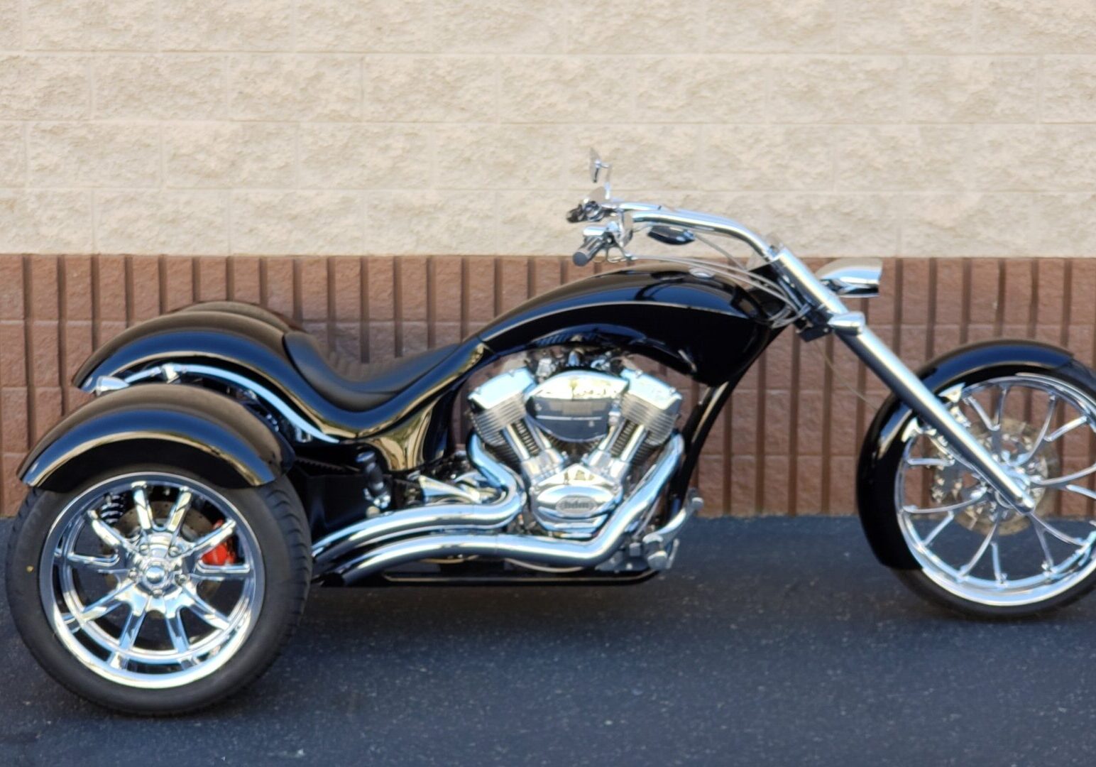 A black motorcycle parked in front of a brick wall.