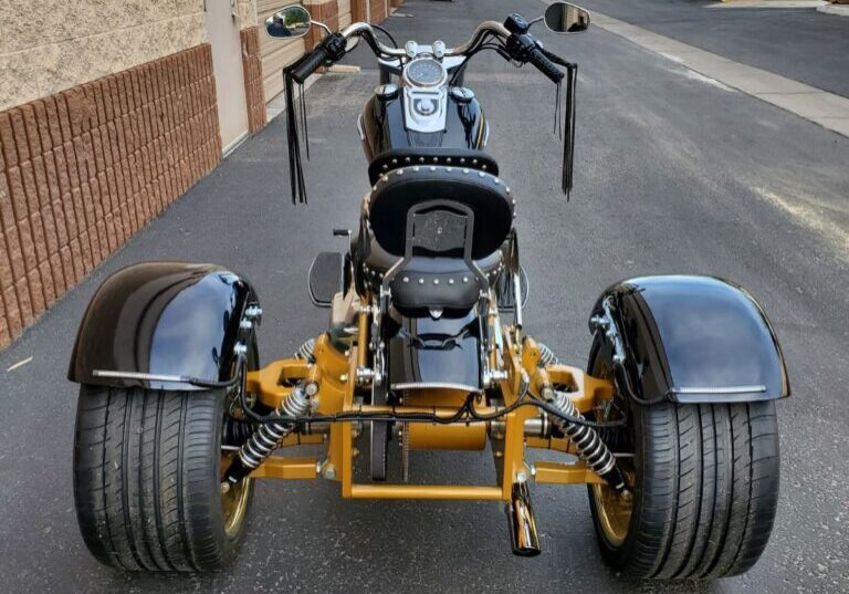 A motorcycle with three wheels parked on the side of a street.